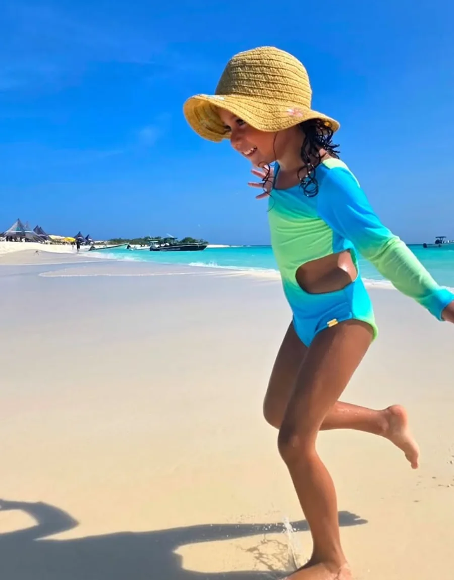 Niña con traje de baño de manga larga en la playa