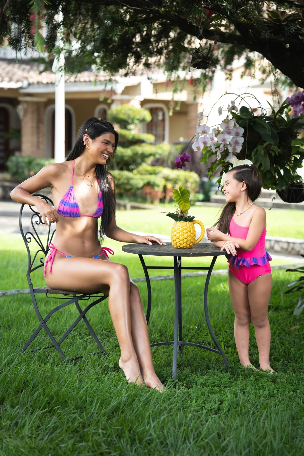 Mujer y niña con trajes estampados en un jardín tropical